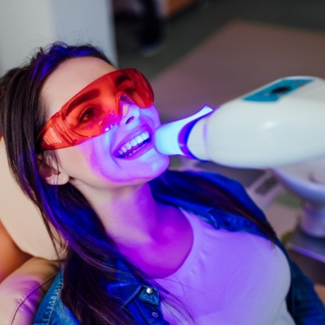 Woman in dental chair receiving professional teeth whitening