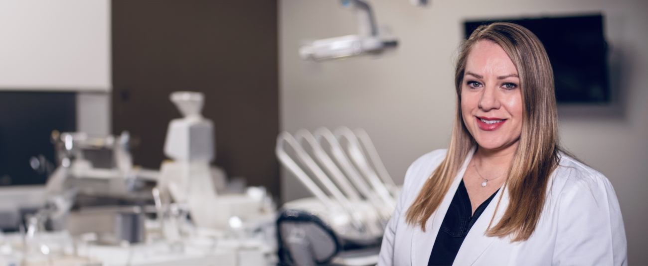 Corinth dentist Doctor Kristina Mackie smiling in white lab coat