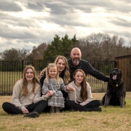 Doctor Mackie sitting in yard with her husband three daughters and dog