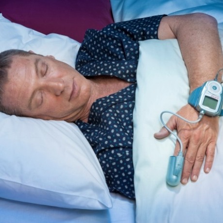 Sleeping man wearing pulse oximeter on his hand