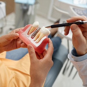 Dentist showing patient model of dental implant