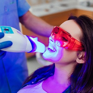 A young woman receiving an in-office teeth whitening treatment