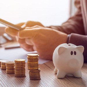 Person using a calculator next to coin stacks and a piggy bank